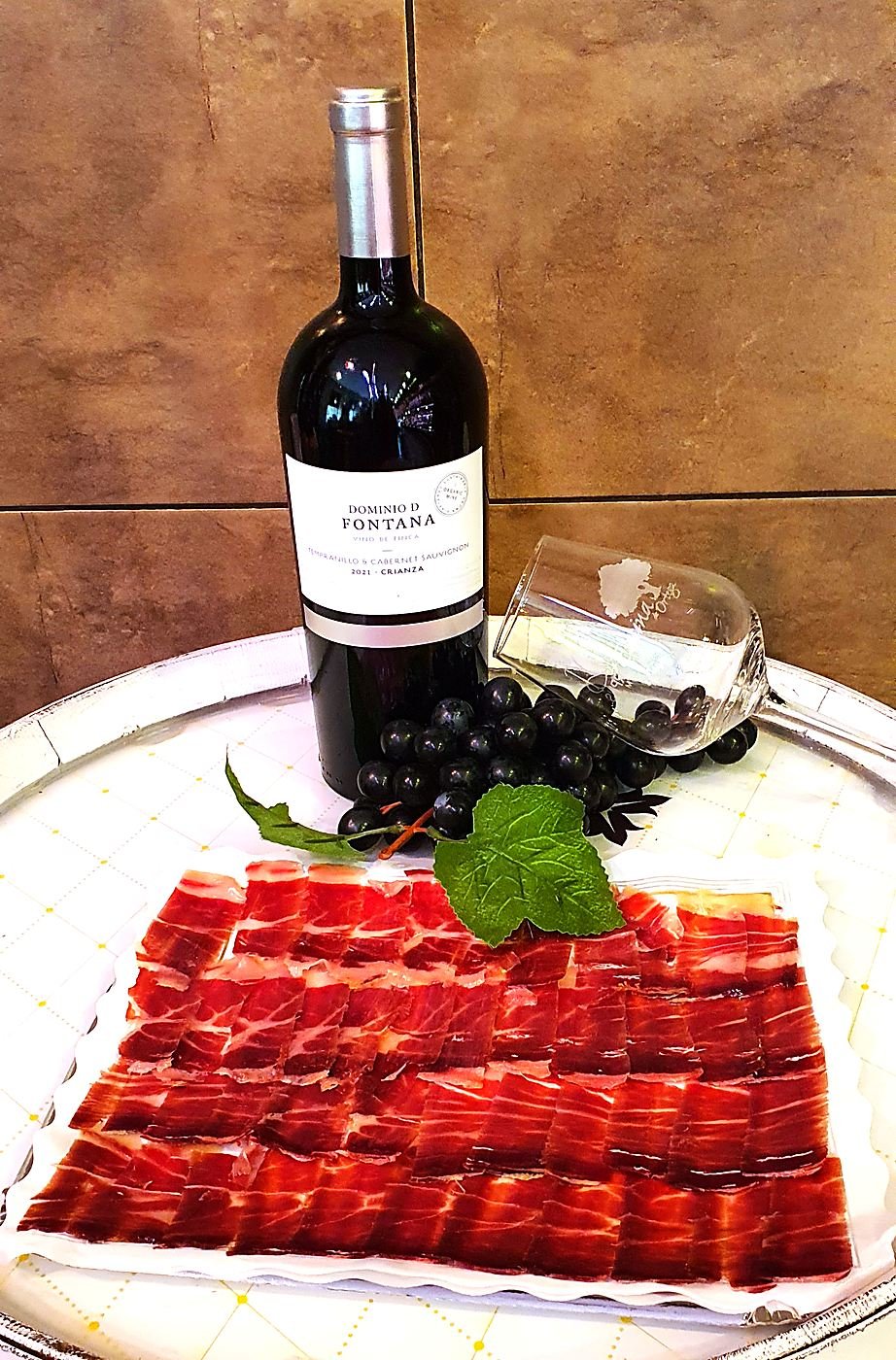 Plate of hand-carved acorn-fed Iberian ham with grapes and Dominio de Fontana wine, Toledo